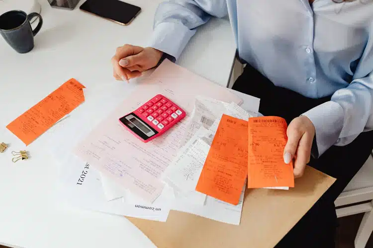 An overhead shot of an employee going through messy paperwork and receipts.
